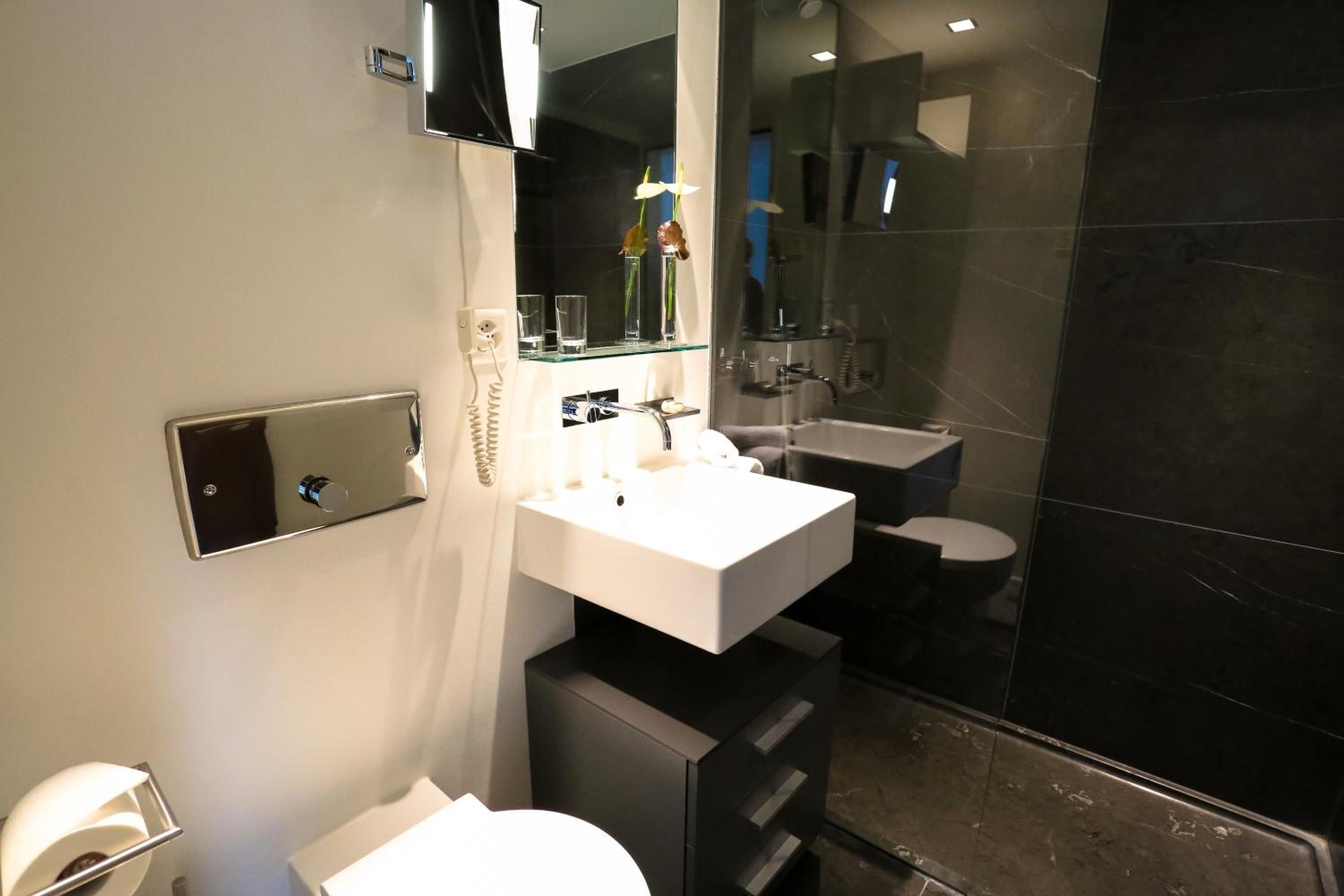 Ein modernes Badezimmer mit einem weißen Waschbecken, einem Spiegel und einer Glasdusche.