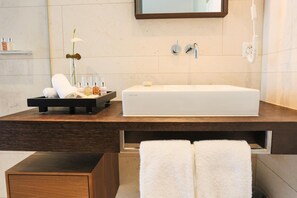 A modern bathroom with a large white sink, a mirror above it, and a towel rack with two towels.