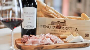 Une bouteille de vin Barbaresco Garasino, une planche à découper en bois avec divers fromages et charcuteries, et une boîte étiquetée « TENUTA CARRETTA » contenant d’autres fromages et charcuteries.