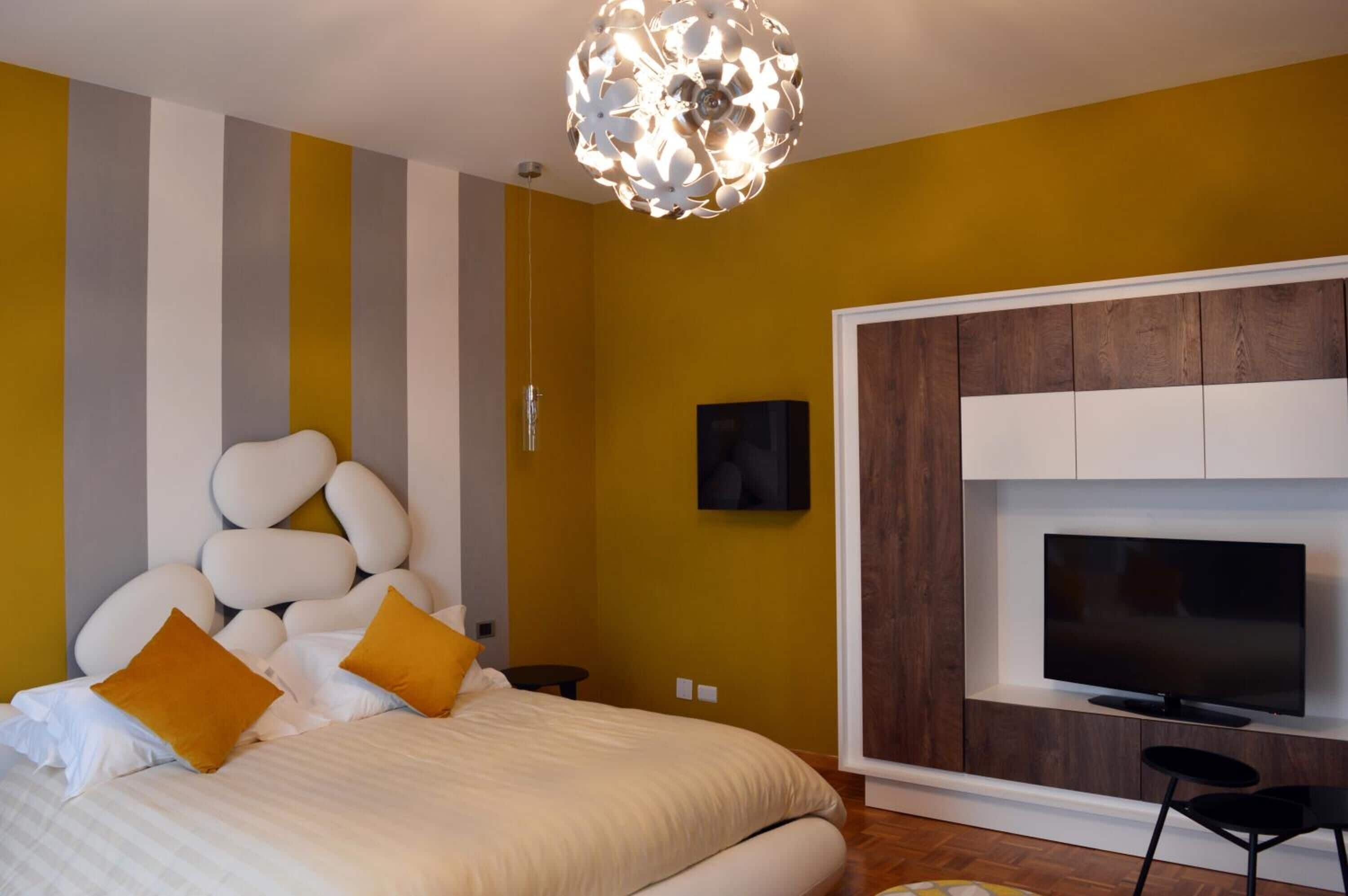 Ein modernes Schlafzimmer mit Bett, Fernseher und einer einzigartigen Deckenleuchte.