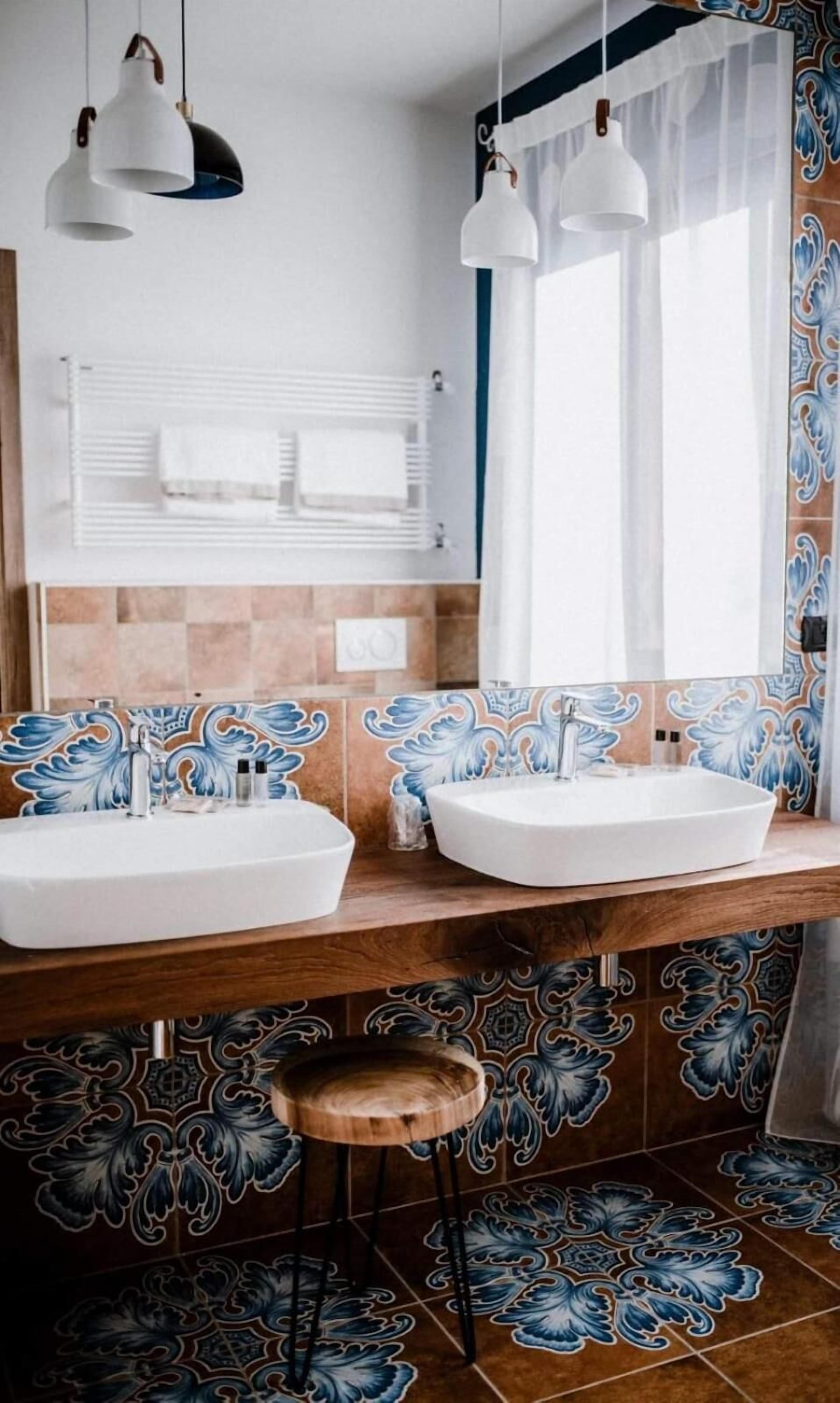 A bathroom with two sinks, a mirror, and a window with curtains.