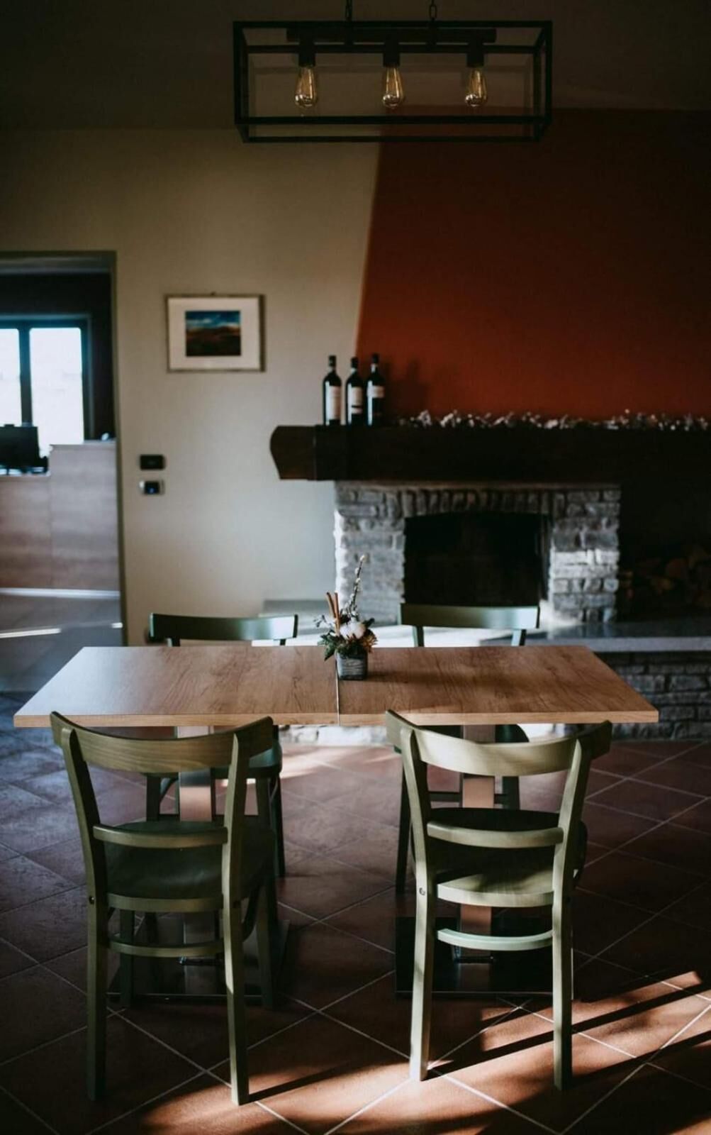 A dining area with a wooden table and chairs, a stone fireplace, and a hanging light fixture.