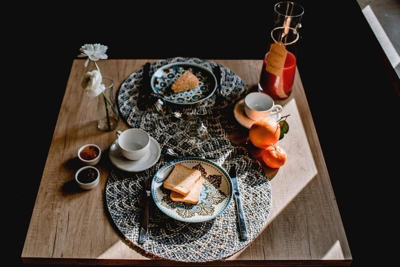 Ontbijt met een bord toast, een kop thee en een glas sap op een tafelkleed met dessin.