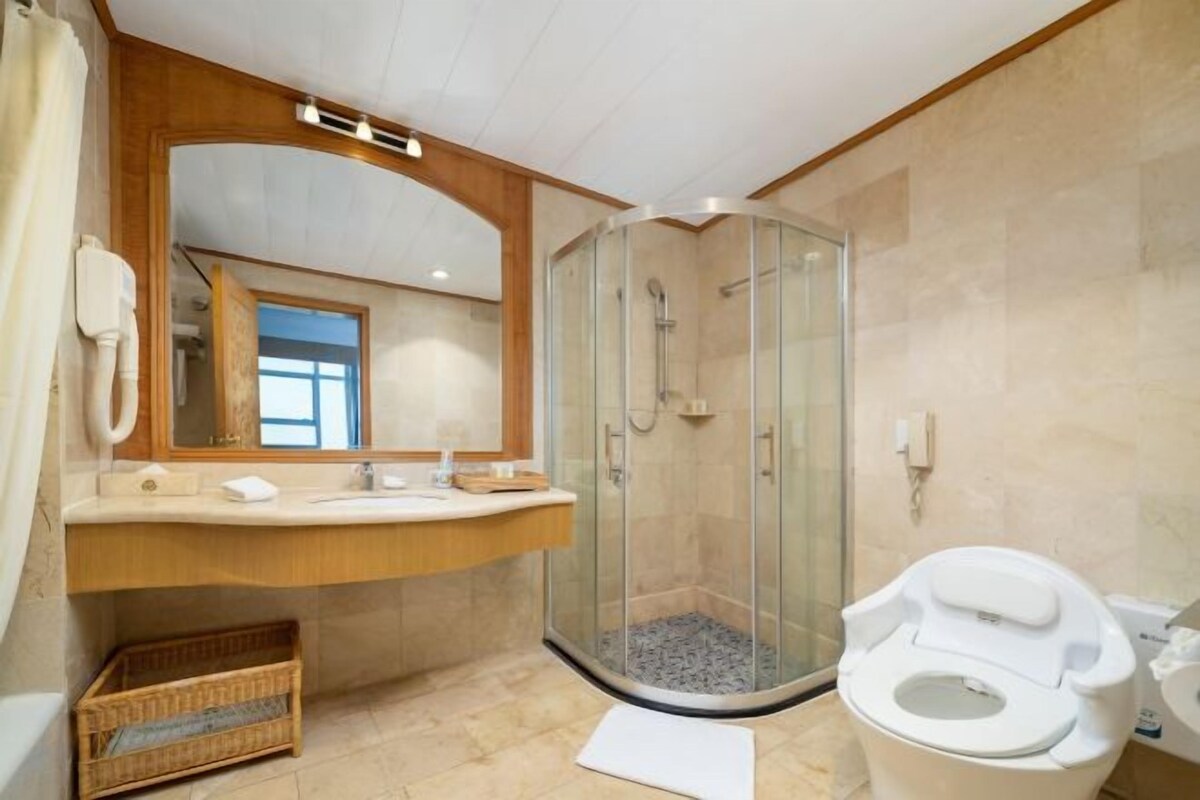 A bathroom with a glass-enclosed shower, a toilet, and a vanity with a mirror.