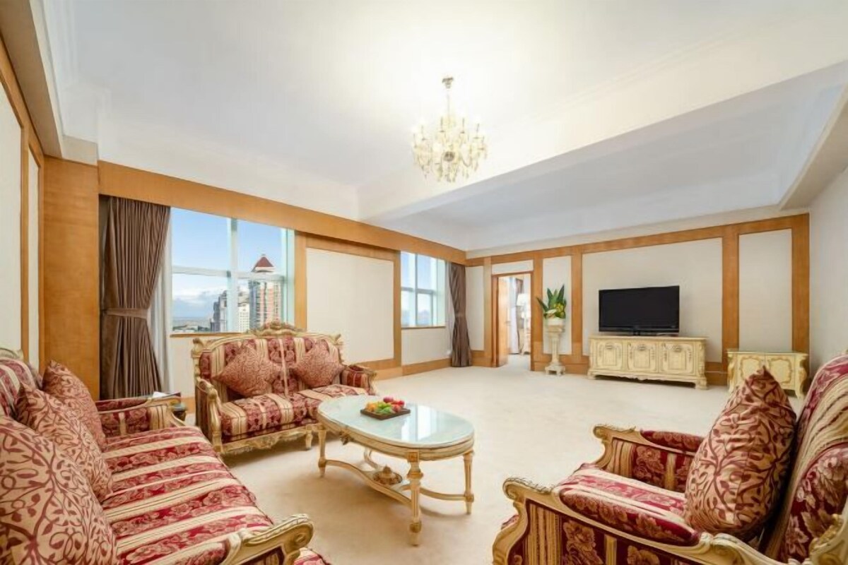A spacious living room with patterned sofas, a coffee table, and a television on a cabinet.