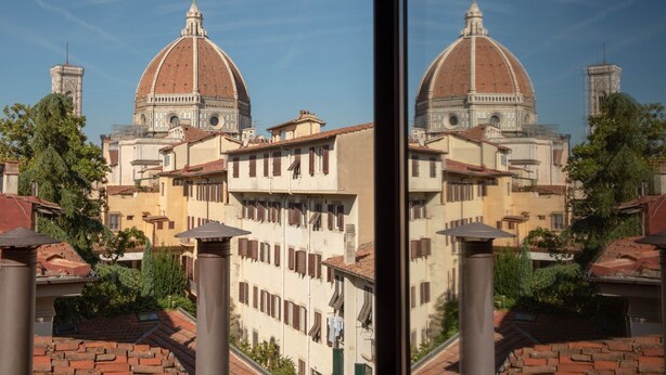 Un bâtiment doté de deux structures en forme de dôme, d’une cour intérieure et dont l’image se reflète dans une fenêtre.