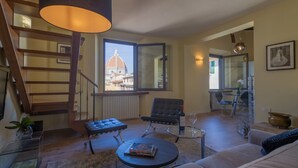 Un salon avec un escalier, une vue sur un dôme, un canapé, une table basse et un fauteuil.