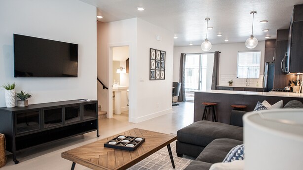 A modern living room with a flat-screen TV, a wooden coffee table, and a gray sofa. - New poolside Luxury townhouse in The Lofts (St. George)