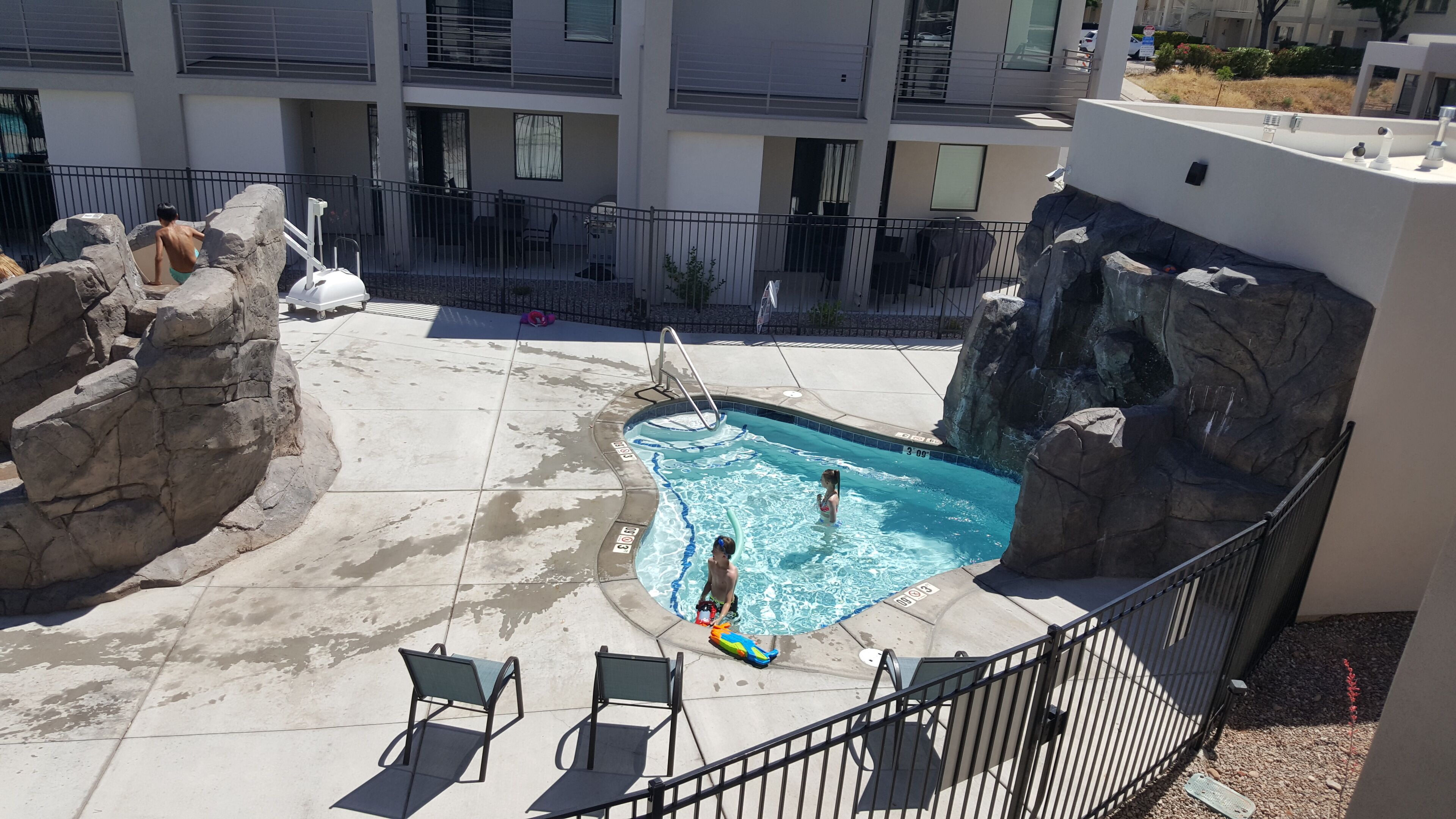 Una piscina amb roques i vista a un edifici residencial.