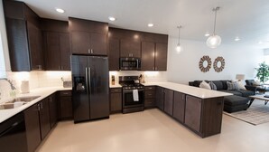 A modern kitchen with dark cabinets, stainless steel appliances, and a large island. - New poolside Luxury townhouse in The Lofts (St. George)