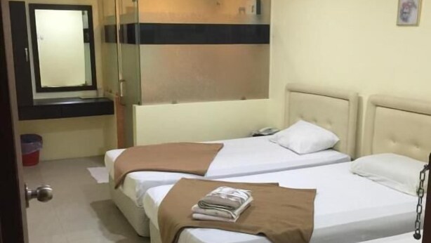 A hotel room with three beds, a large mirror, an air conditioning unit, and a small window. - Rafayeh Hotel (Seremban)