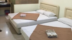 A hotel room with two beds, each with a brown blanket and a pillow. There is a small table with a book and a cup, and a mirror on the wall. - Rafayeh Hotel (Seremban)