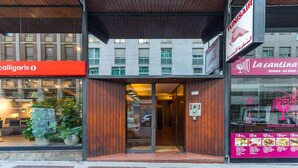 Un edificio con una facciata moderna, caratterizzato da un ingresso in legno e cartelli con la scritta 'TUNISAIR' e 'La Cantina'.