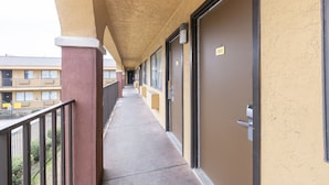 A corridor with doors numbered 253, a concrete floor, and a balcony with a metal railing. - Southern Comfort Hotel (Tulsa)