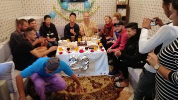 A group of people gathered around a table with a cake, balloons, and a number '23' sign.