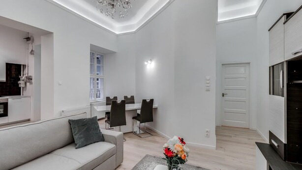 Una sala moderna con un sofá, comedor y televisor.