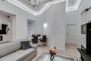 A modern living room with a sofa, dining area, and a TV. - Pelicanstay at 5th District (Budapest)