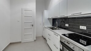 Una cocina moderna con armarios blancos, un protector contra salpicaduras negro y electrodomésticos de acero inoxidable.