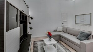 Una sala moderna con una televisión de pantalla plana, un sofá, una mesa de centro y una araña.