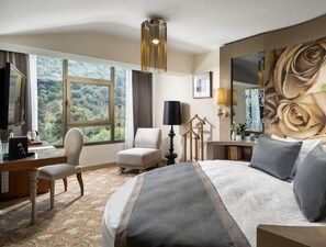 A hotel room with a large bed, a desk with a chair, a television, and a view of the outdoors. - Kaya Izmir Thermal & Convention (Izmir)