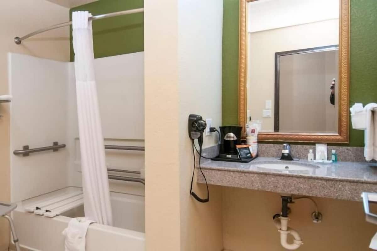 Een badkamer met een douche, een wastafel met spiegel en een handdoekhouder.