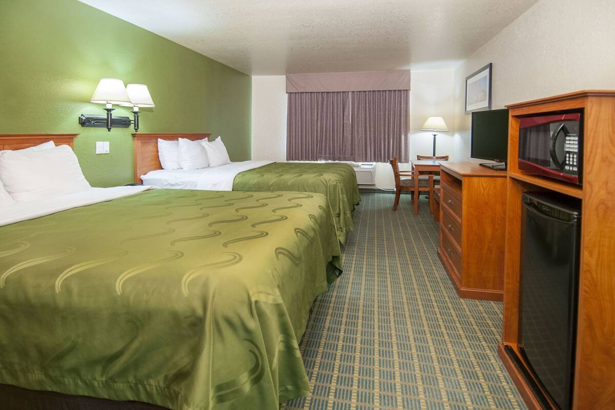 Een hotelkamer met twee bedden, een televisie, een magnetron en een klein bureau.
