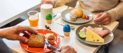 Un desayuno con diversos alimentos en platos, incluyendo pan, queso y un muffin.
