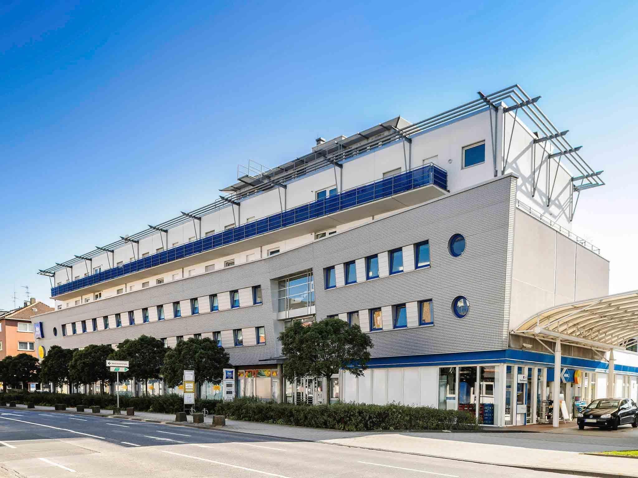 A modern building with a flat roof, multiple windows, and a covered entrance.