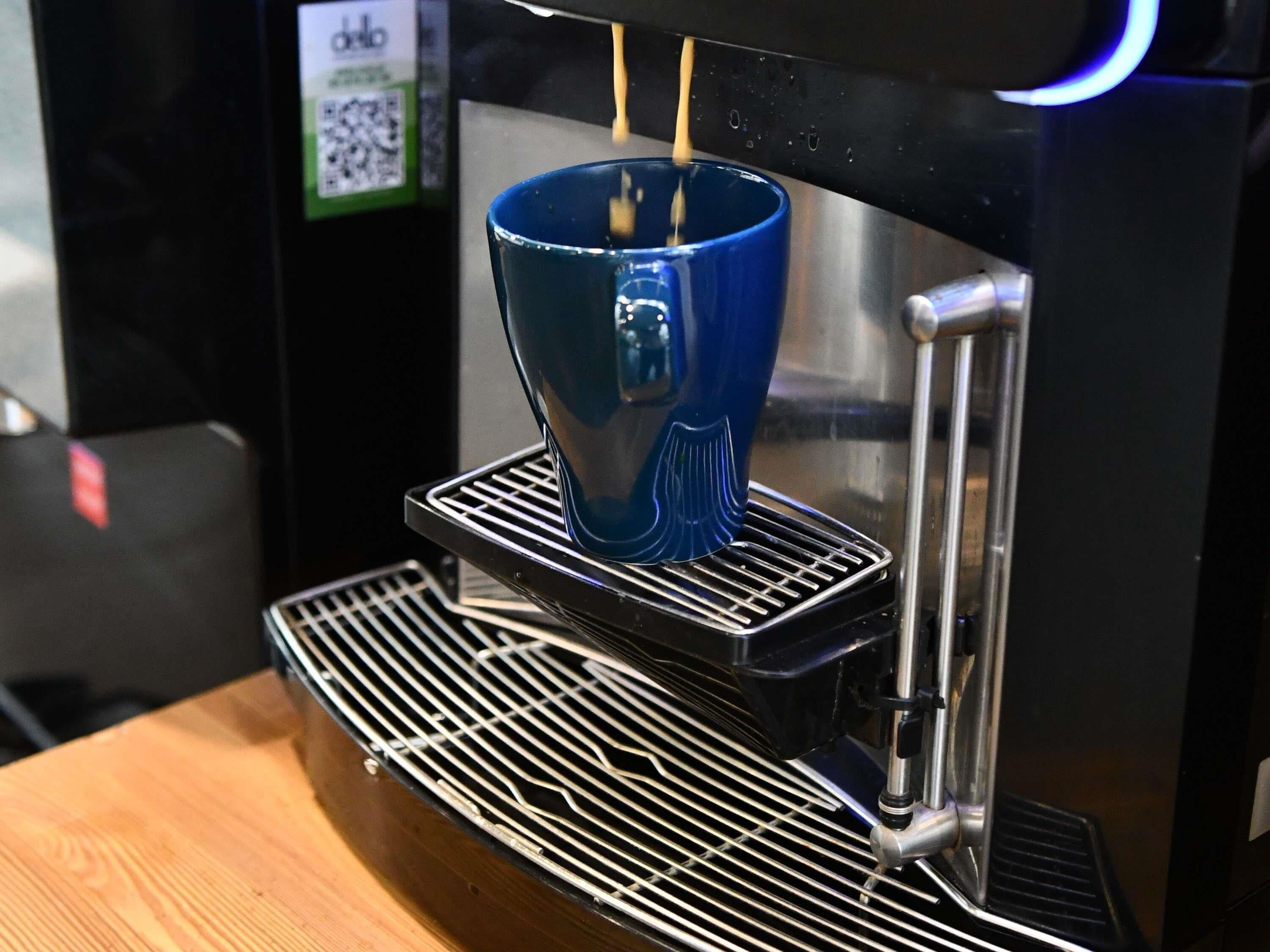 A coffee machine with a blue cup on its drip tray.