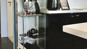 A reception desk with a glass display case containing a white paper model of a building, a potted plant, and some stationery items. - Ibis Budget Wroclaw Stadion (Wroclaw)
