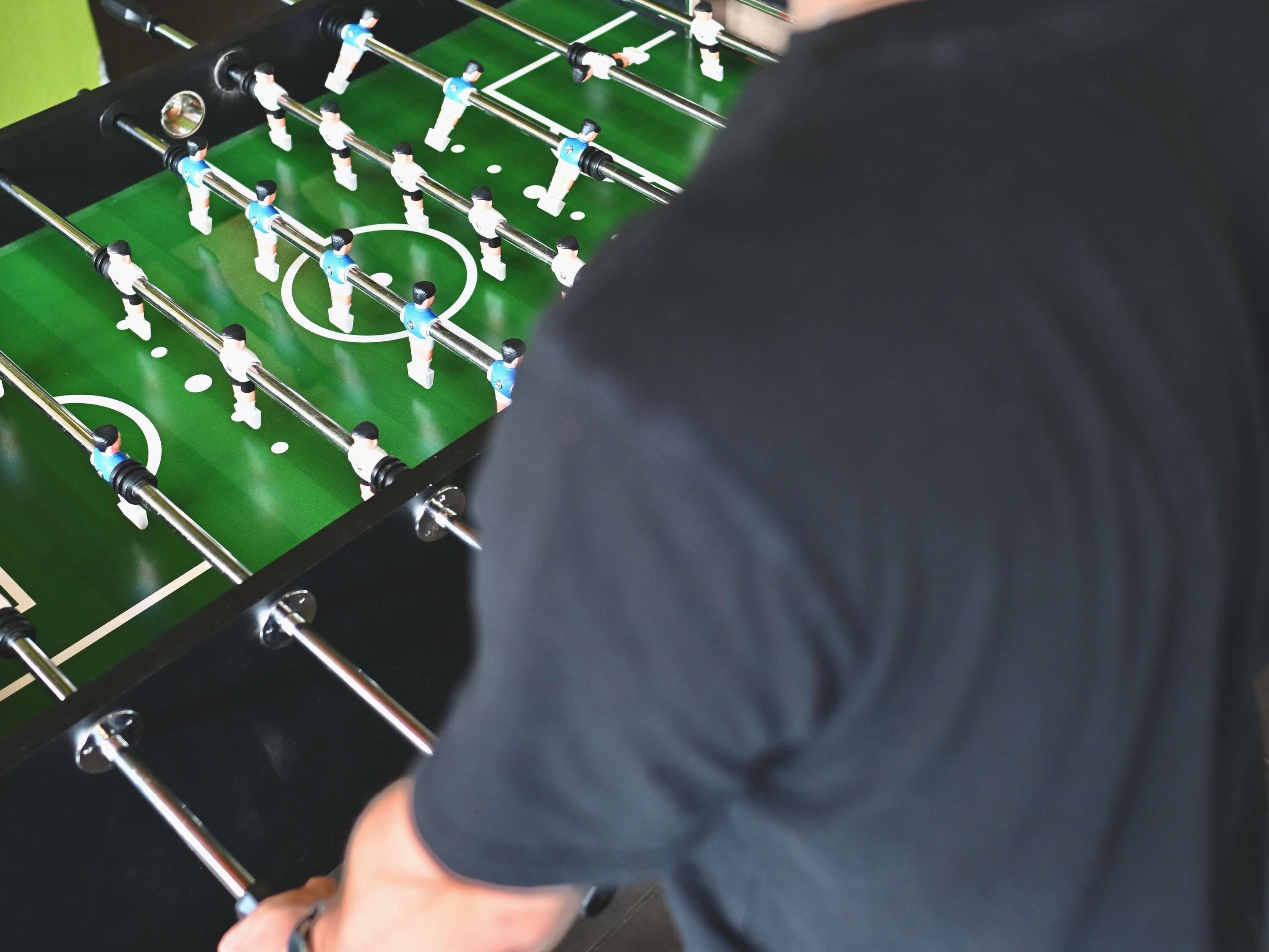 Um close-up de uma mesa de futebol de mesa com superfície verde e barras de metal.