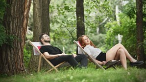 Two people relaxing on a wooden deck in a forested area with trees and greenery around. - Ibis Budget Wroclaw Stadion (Wroclaw)