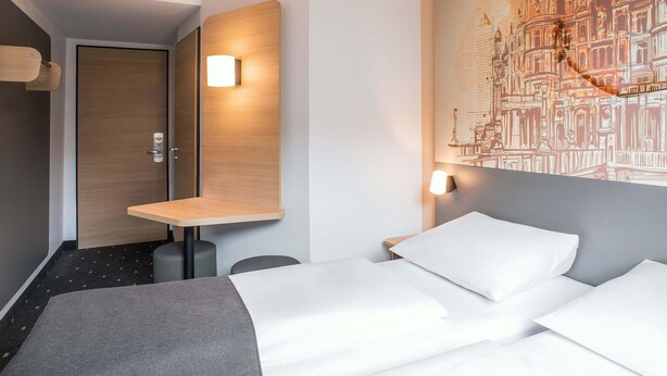Une chambre d’hôtel avec un lit, un bureau et une lampe fixée au mur.