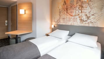 A hotel room with a bed, a desk, and a wall-mounted artwork depicting a cityscape.
