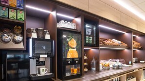Un bar à petit-déjeuner moderne, équipé d’une machine à café, d’une sélection de thés et d’un présentoir de fruits.