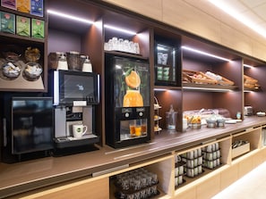 Eine moderne Frühstückstheke mit Kaffeemaschine, Teeauswahl und Obstpräsentation.