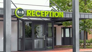 L’entrée d’un hôtel-restaurant de type « bed and breakfast », avec une porte en verre et une enseigne au-dessus.