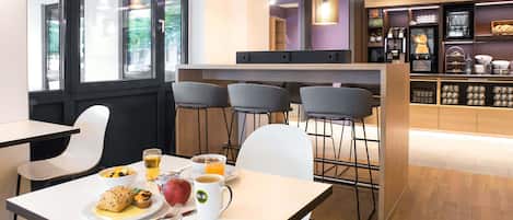 A modern cafe with a white table, chairs, and a breakfast setting including a plate of food, a mug, and a glass of orange juice.