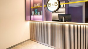 Un espace d’accueil avec une enseigne indiquant « BAR », une autre indiquant « CHAMBRES D’HÔTES », et un comptoir doté d’un écran d’ordinateur.