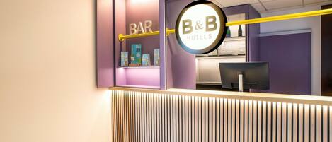 A reception area with a 'BAR' sign, a 'B&B' sign, and a counter with a computer monitor.