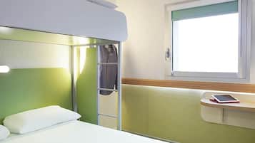 A bunk bed with a green headboard, a bedside table with a tablet, and a window with a view.