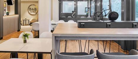A modern hotel reception area with a reception desk, seating area, and large windows offering views of the outside.
