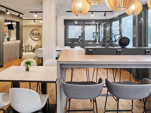 A modern hotel reception area with a reception desk, seating area, and large windows offering views of the outside. - B&B HOTEL Wiesbaden-Ost (Wiesbaden)