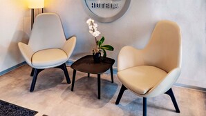 Una habitación de hotel con dos sillones, una mesita con una planta y un cartel en la pared que dice "B&B HOTELS".