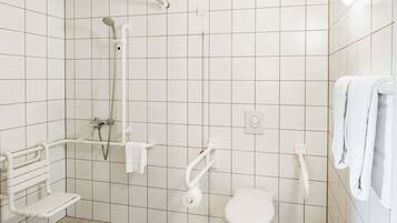 A small, white bathroom with a shower, toilet, and a bench.