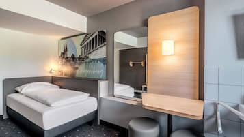 Ein modernes Hotelzimmer mit einem Bett, einem Spiegel, einer Wandleuchte und einem Stadtbild.