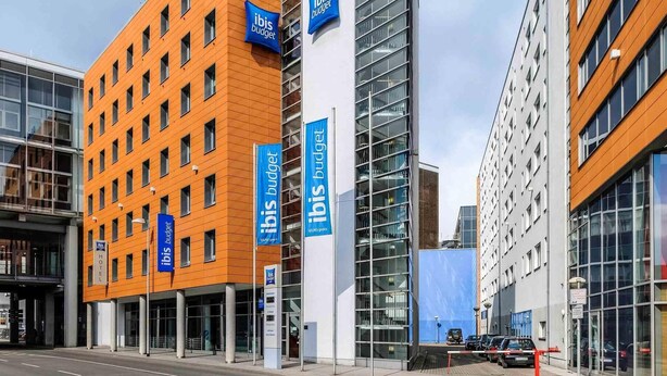 A modern hotel with multiple floors, prominent signage, and a glass facade. - Ibis Budget Hannover Hauptbahnhof (Hannover)