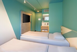 A hotel room with two beds, a sink, and a television. - Ibis Express Hannover Central Station (Hannover)