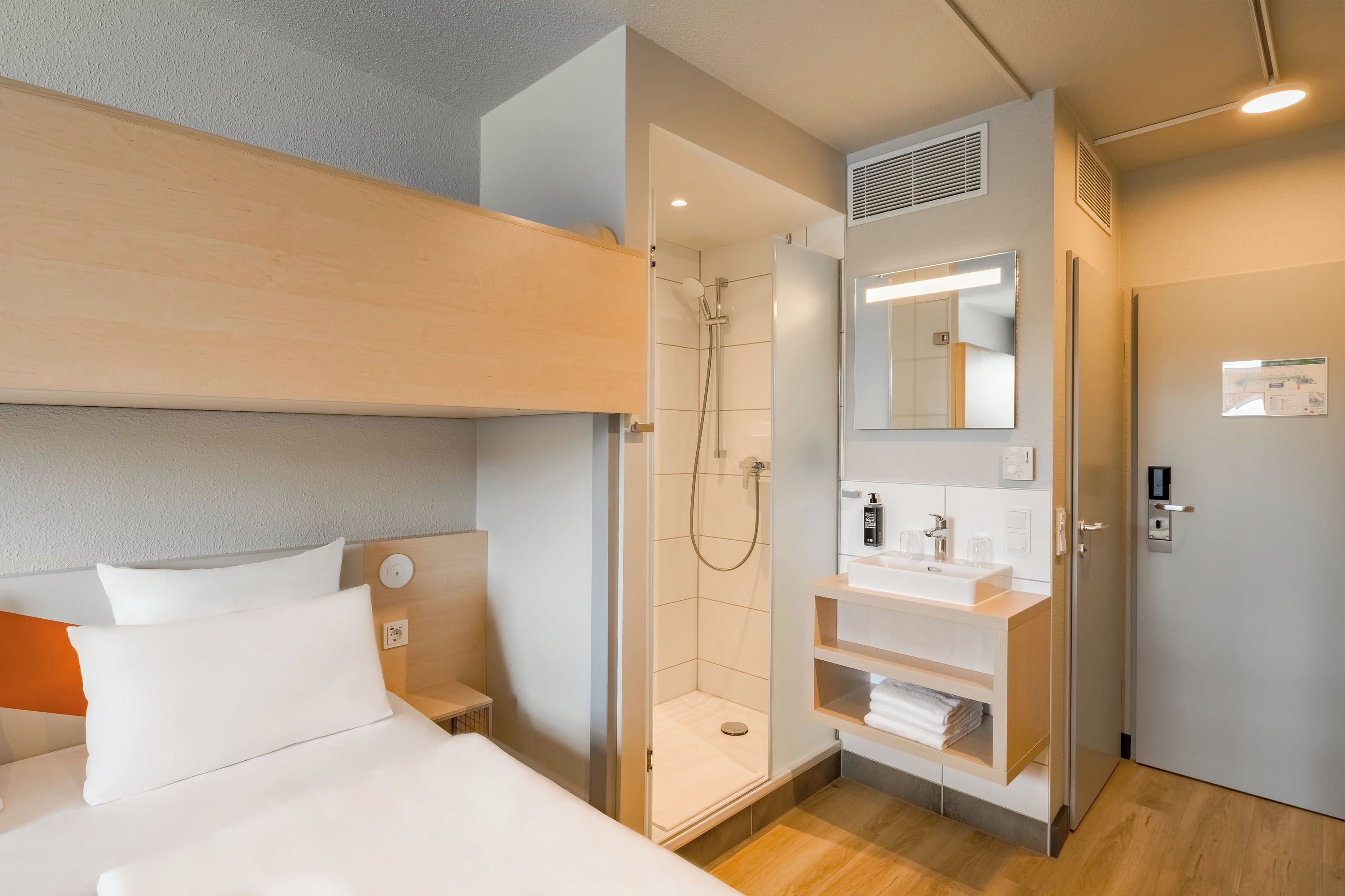 Ein Hotelzimmer mit Bett, Dusche, Waschbecken und Spiegel.