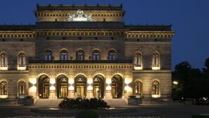 A large, historic building with a central entrance, arched windows, and a statue on the roof. - Ibis Budget Hannover Hauptbahnhof (Hannover)